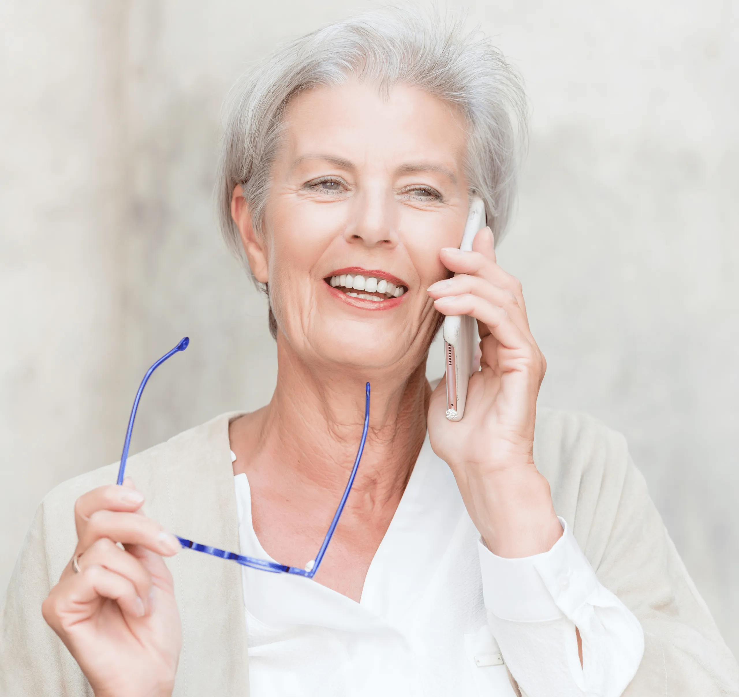 An elderly lady on the mobile phone call in front of a wall